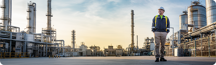 Man in hard hat in front of industrial plant.